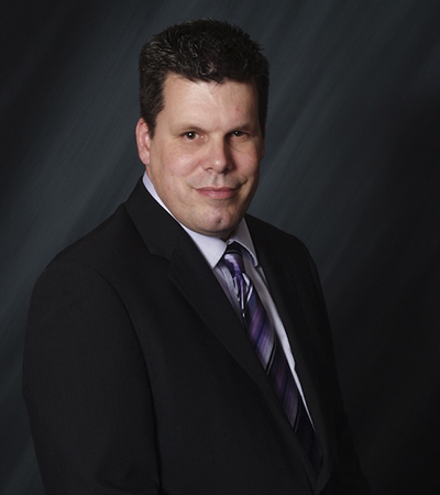 Man with short brown hair wearing a suit and tie