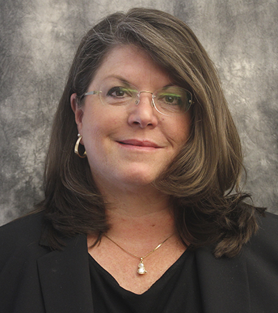 Woman with shoulder length brown hair wearing glasses and a dark suit