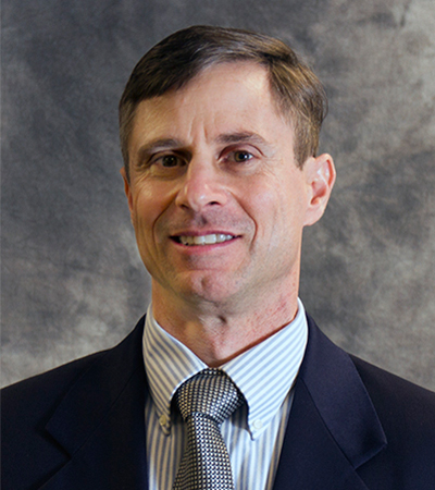 Man with short brown hair wearing a suit and tie