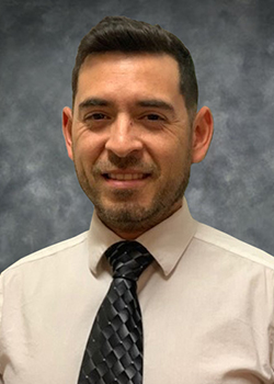 Man wearing tan button up shirt with dark grey tie