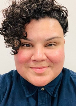 woman with short curly hair wearing a blue button up shirt