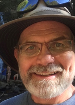 Man with white beard wearing a hat and prescription glasses