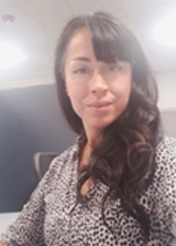 Woman with long brown wavy hair wearing a black and white blouse