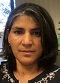 Woman with short black hair wearing a black bouse with floral pattern on collar