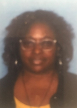 Woman with curly black hair wearing prescription glasses and a yellow shirt