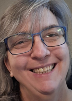 Woman with grey hair wearing blue rimmed prescription glasses