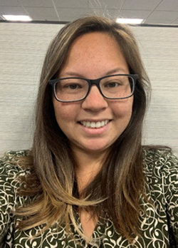 Woman medium length brown hair wearing prescription glasses and black and gold patterned blouse