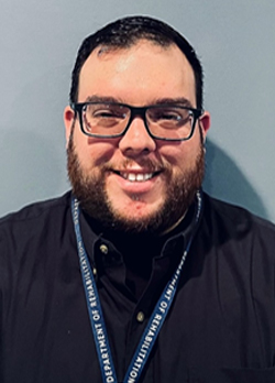 Man with short, black hair wearing a navy button up shirt and DOR lanyard