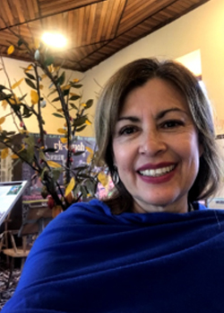 Woman with short, straight brown hair wearing a blue shawl