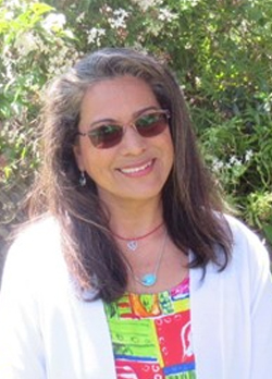 woman wearing sunglasses and a white sweater vest over a colorful blouse
