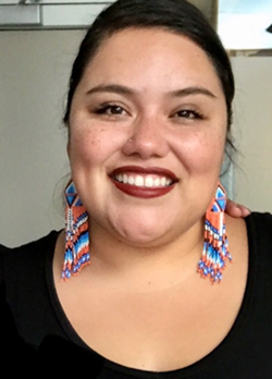 Woman with dark hair pulled back wearing colorful earrings