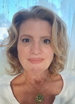 Woman with short blonde hair wearing a white shirt with jade necklace