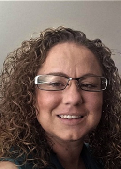 woman with short, curly, brown hair wearing rectangular glasses